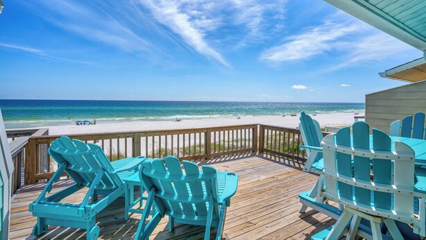 Un pontile in legno con poltrone Adirondack color turchese che si affaccia su una spiaggia.