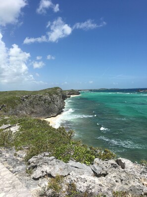 Un paisaje costero con terreno rocoso, una playa arenosa y el océano.