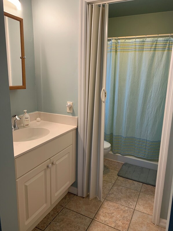 Une salle de bain avec un lavabo, un miroir et un rideau de douche.