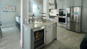 A modern kitchen with stainless steel appliances, a marble countertop, and a central island. - Gated Waters Edge, deeded beach, chair set up, private pool, 5 bed\5+ sleeps 16 (Rosemary Beach)