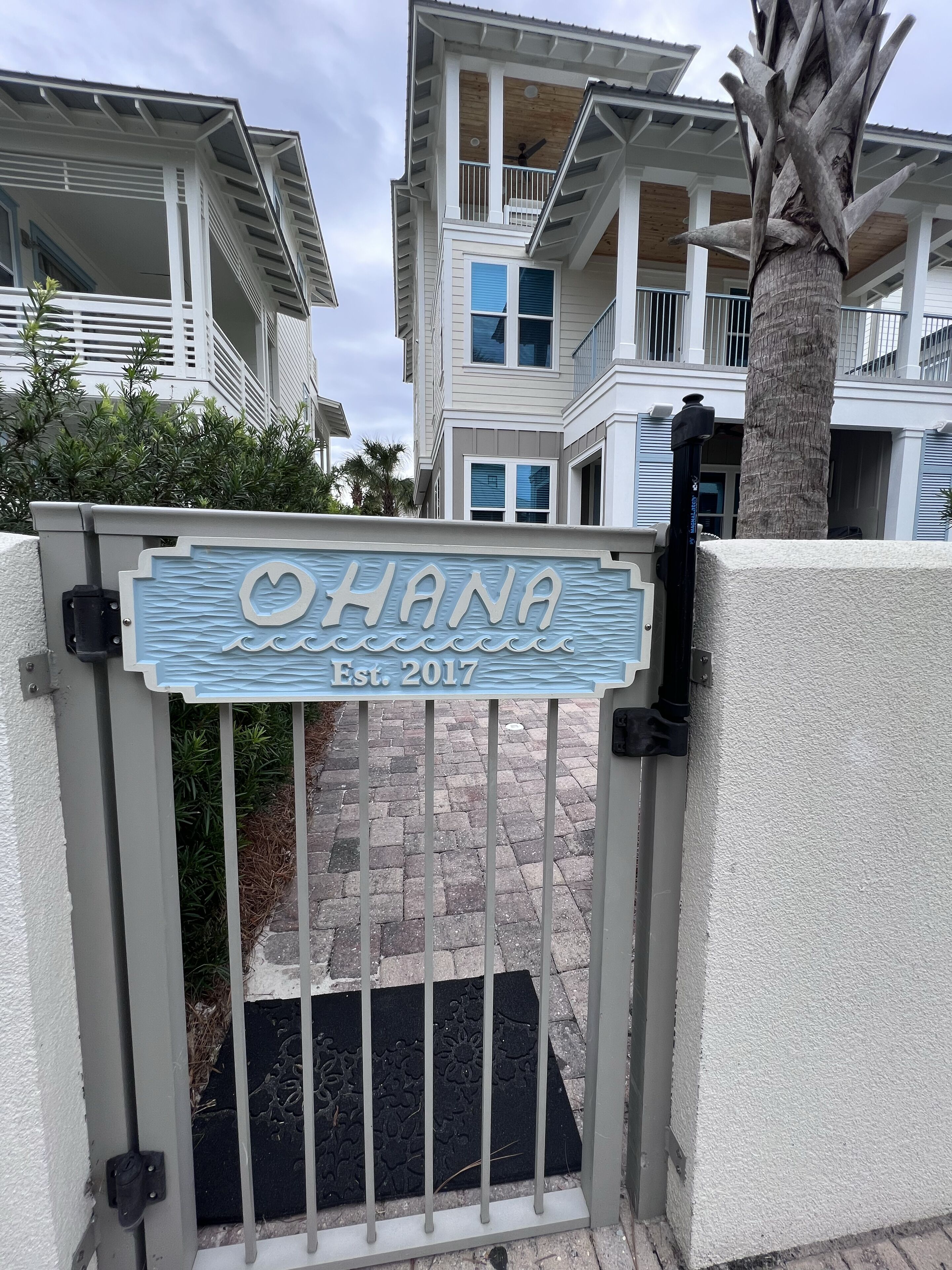 Una entrada tancada amb un senyal que diu "HANA Est. 2017" i una palmera a prop.