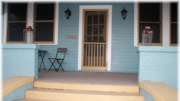 A porch with steps leading to a door, two wall-mounted lanterns, and a folding chair. - Beautiful New Orleans Gem Close To Downtown (New Orleans)