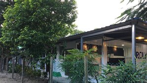 A building with a covered outdoor area, surrounded by trees and a fence.