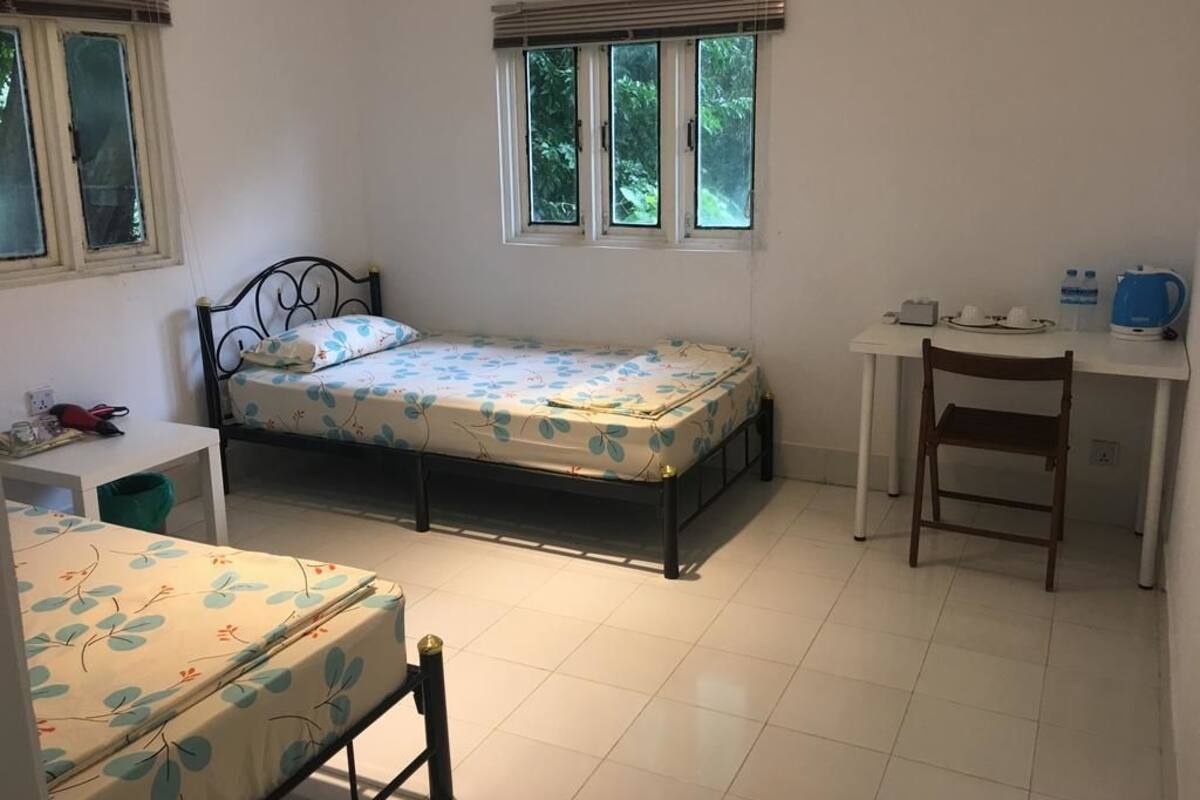 A bedroom with a bed, a desk, a chair, and a window.