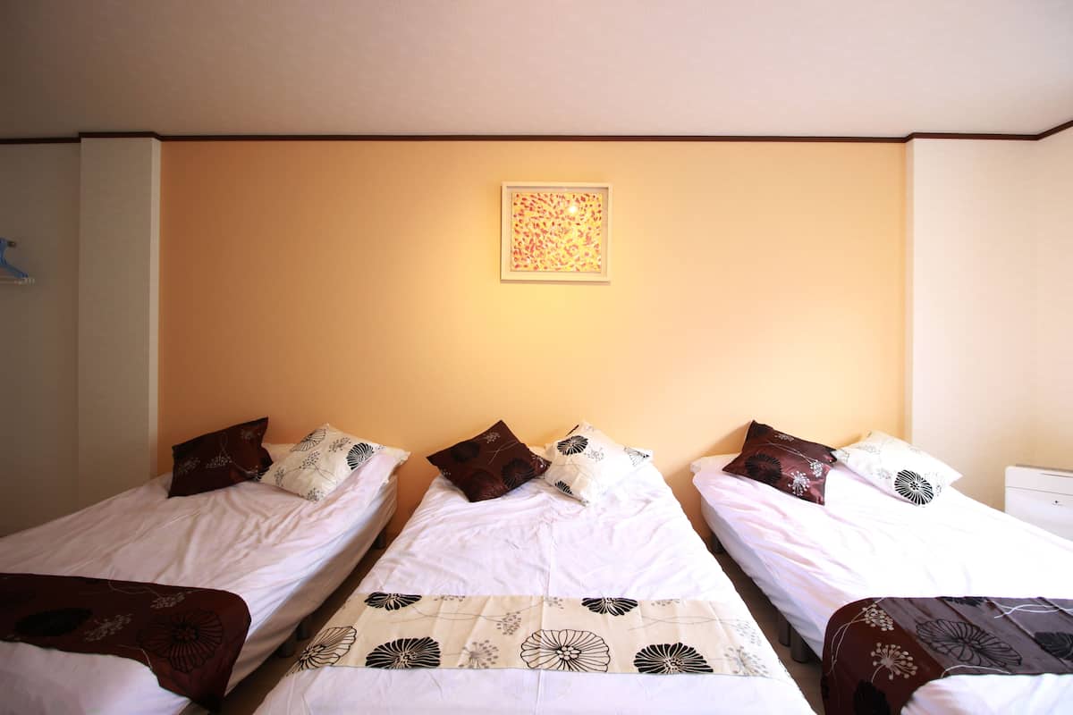 A hotel room with three single beds, each with a distinct floral-patterned bedspread.