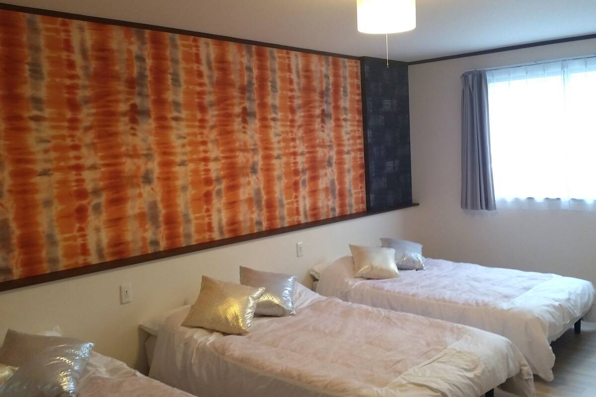 A hotel room with two beds, a large abstract painting on the wall, and a window with curtains.