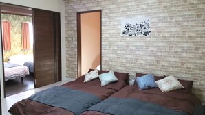 A bedroom with a brick-patterned wall, a bed with multiple pillows, and a door leading to another room. - Mansion Kawata (Osaka)