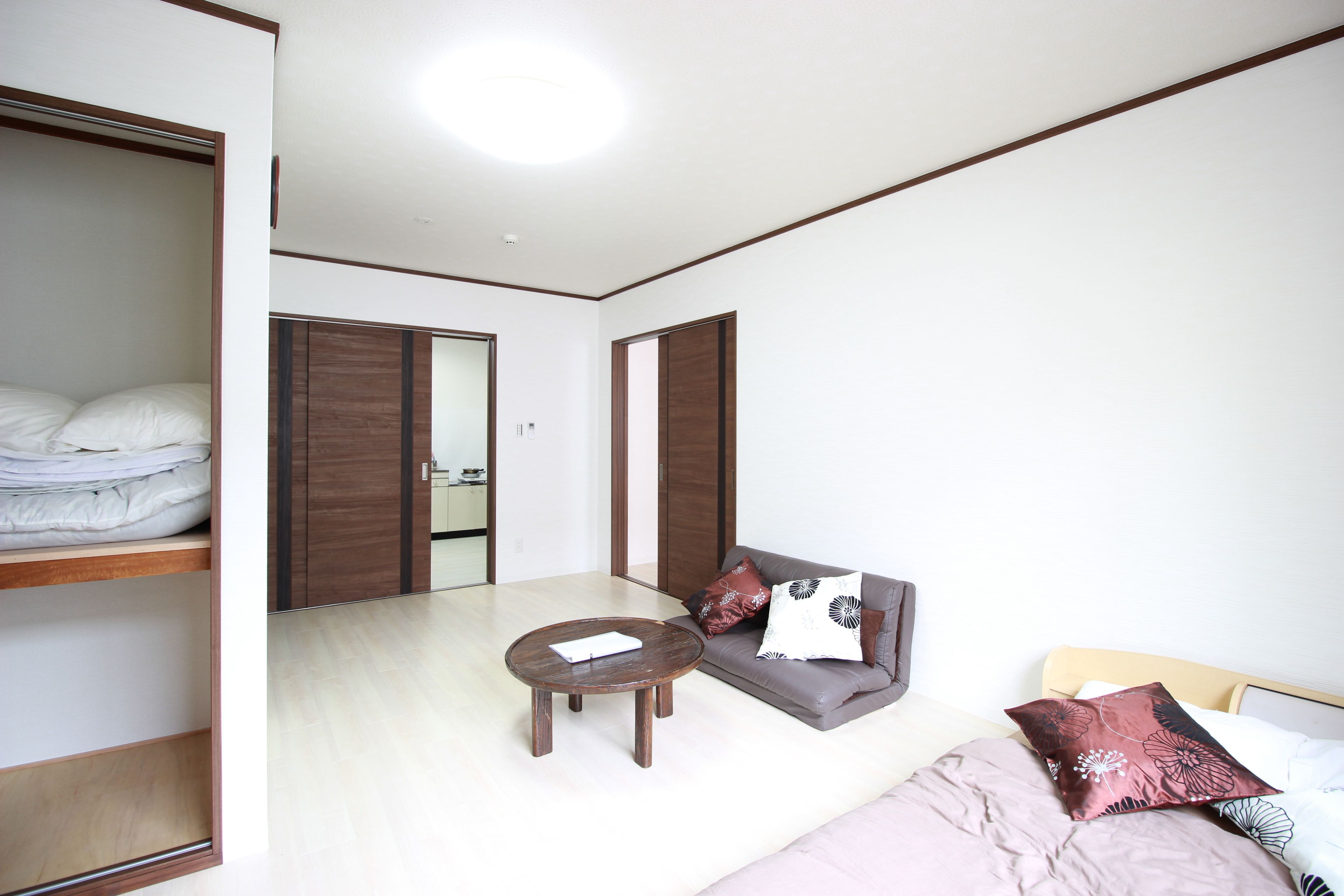 A room with a bed, a sofa, a round wooden table, and a wardrobe.