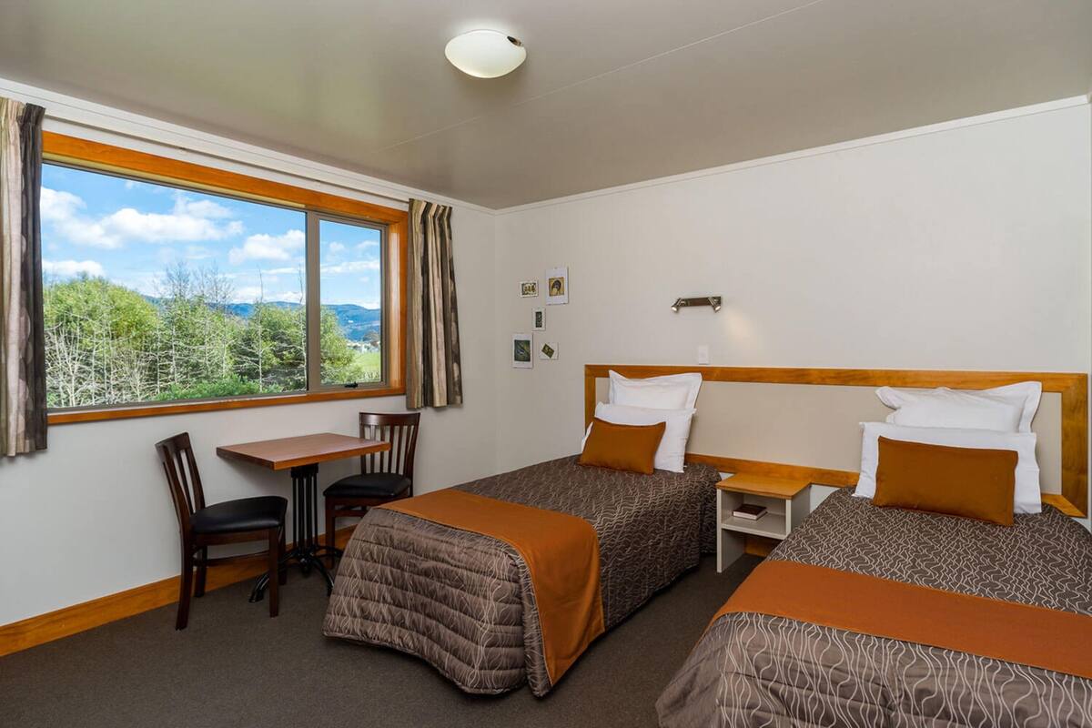 Ein Hotelzimmer mit zwei Betten, einem Schreibtisch und einem Stuhl.
