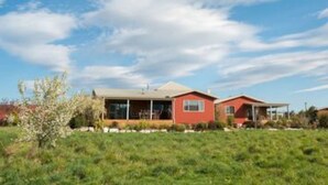 A modern two-story house with a large front lawn, a covered patio, and a clear blue sky. - Eden's Edge Lodge (Riwaka)