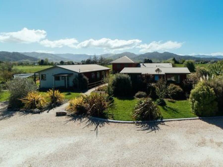 Una casa de dos pisos con camino de grava y un jardín bien cuidado.