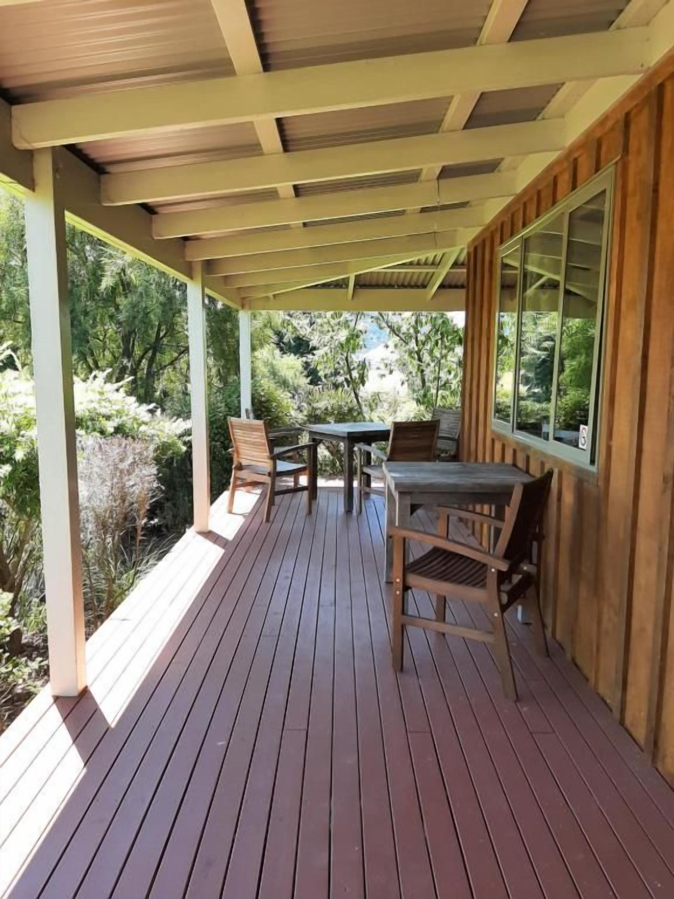 A covered outdoor area with a wooden deck, a table, and chairs.