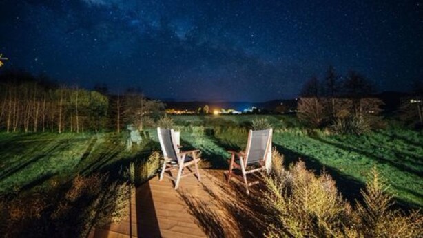 A night scene with two chairs on a wooden deck under a starry sky. - Eden's Edge Lodge (Riwaka)