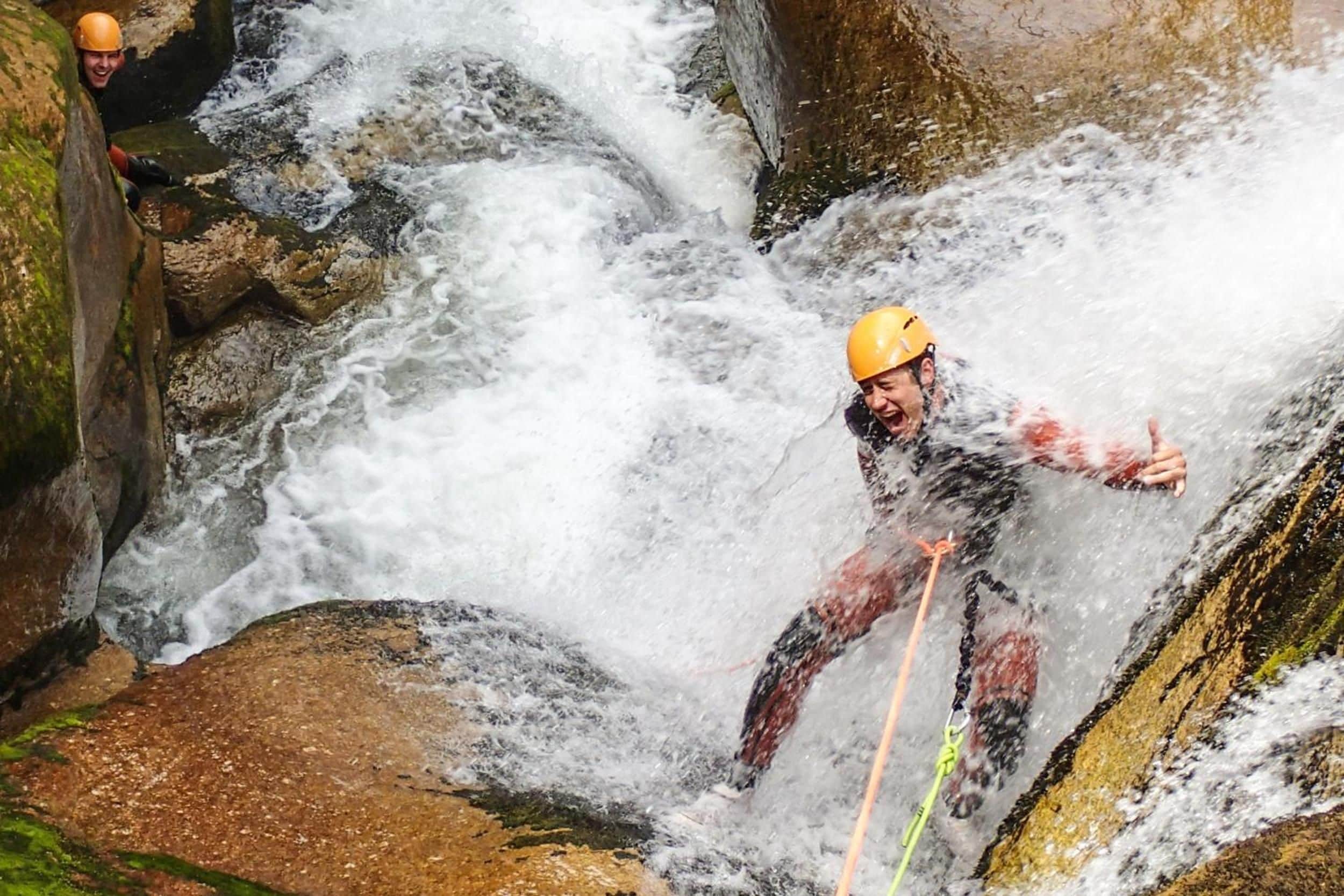A person rappelling down a rocky waterfall.