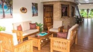 A wooden-floored living area with a sofa and armchairs, a coffee table, and a stone wall.