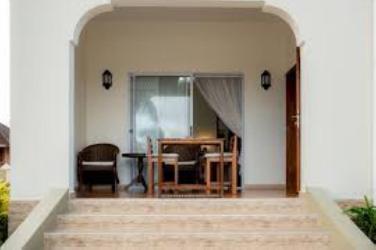 Un escalier menant à une pièce où se trouvent une table, des chaises, un fauteuil et une lampe.