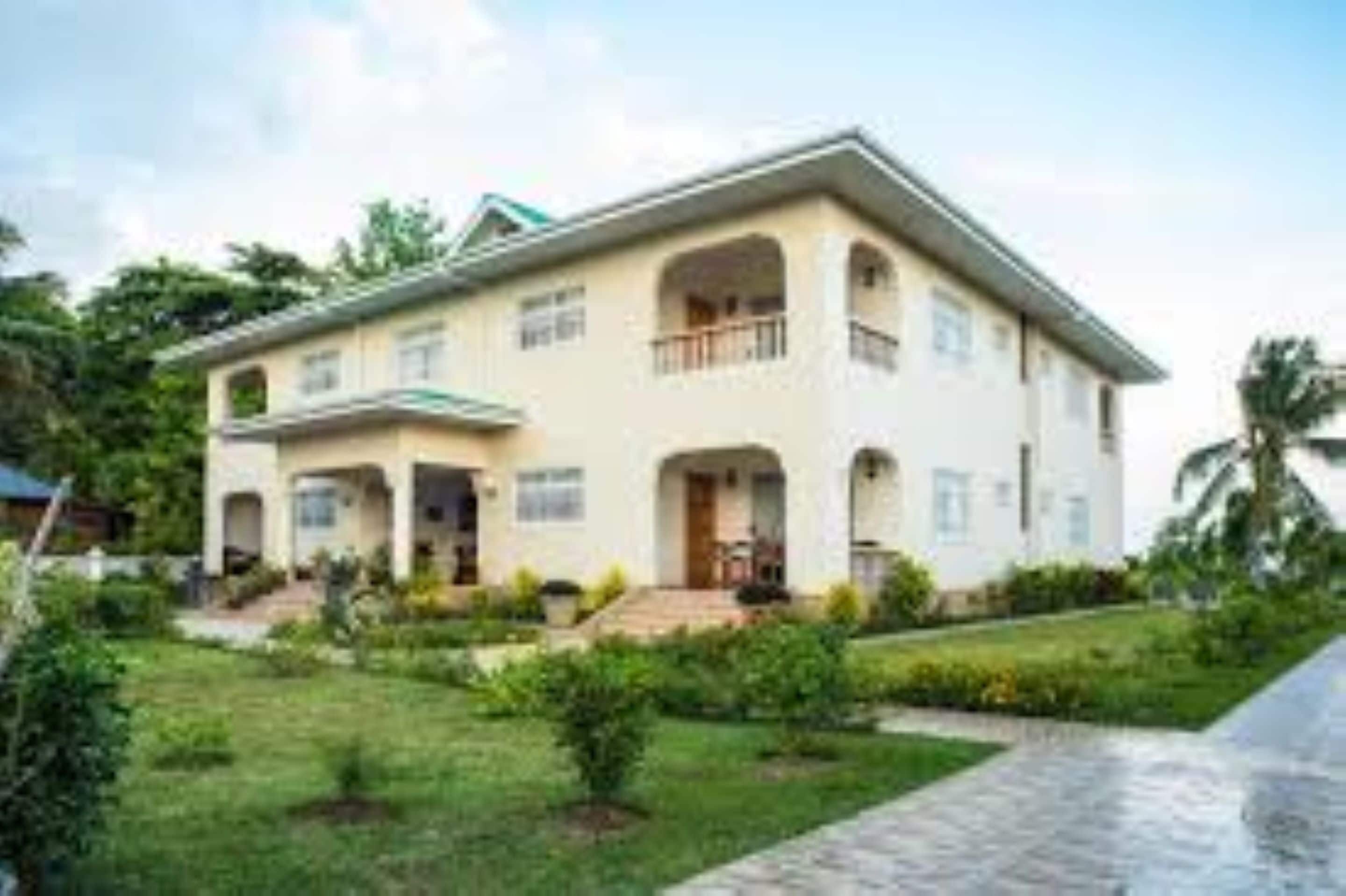 A two-story house with a front porch, a small garden, and a paved driveway.