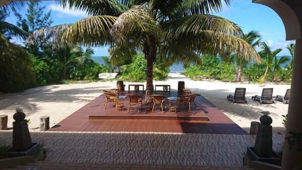 A beachside lounge with wooden furniture and a view of the ocean. - Seashell Beach Villa (Praslin Island)