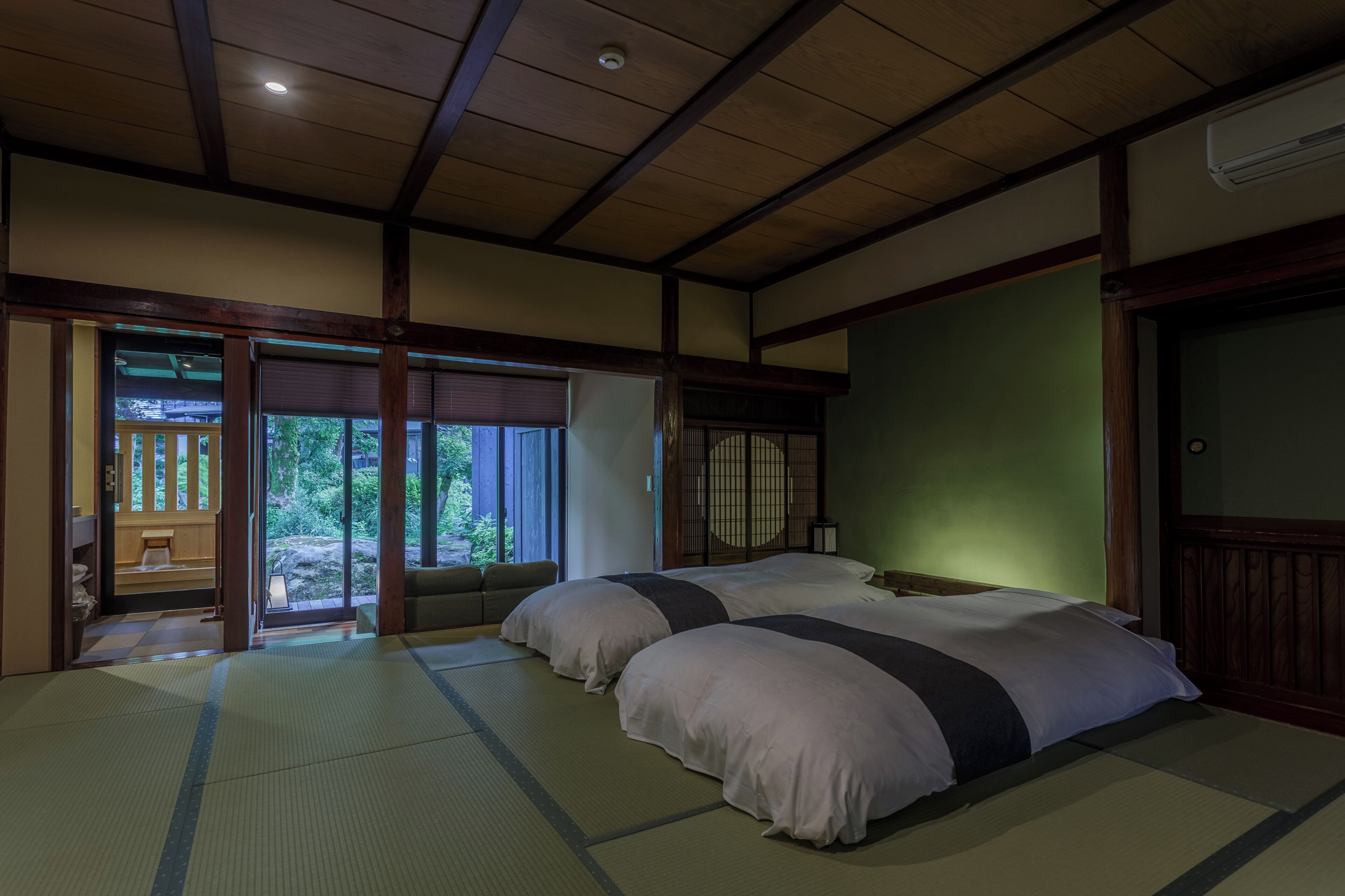 Ein traditioneller japanischer Raum mit Tatami-Boden, einer Holzbalkendecke und einer Schiebetür, die auf einen Balkon führt.
