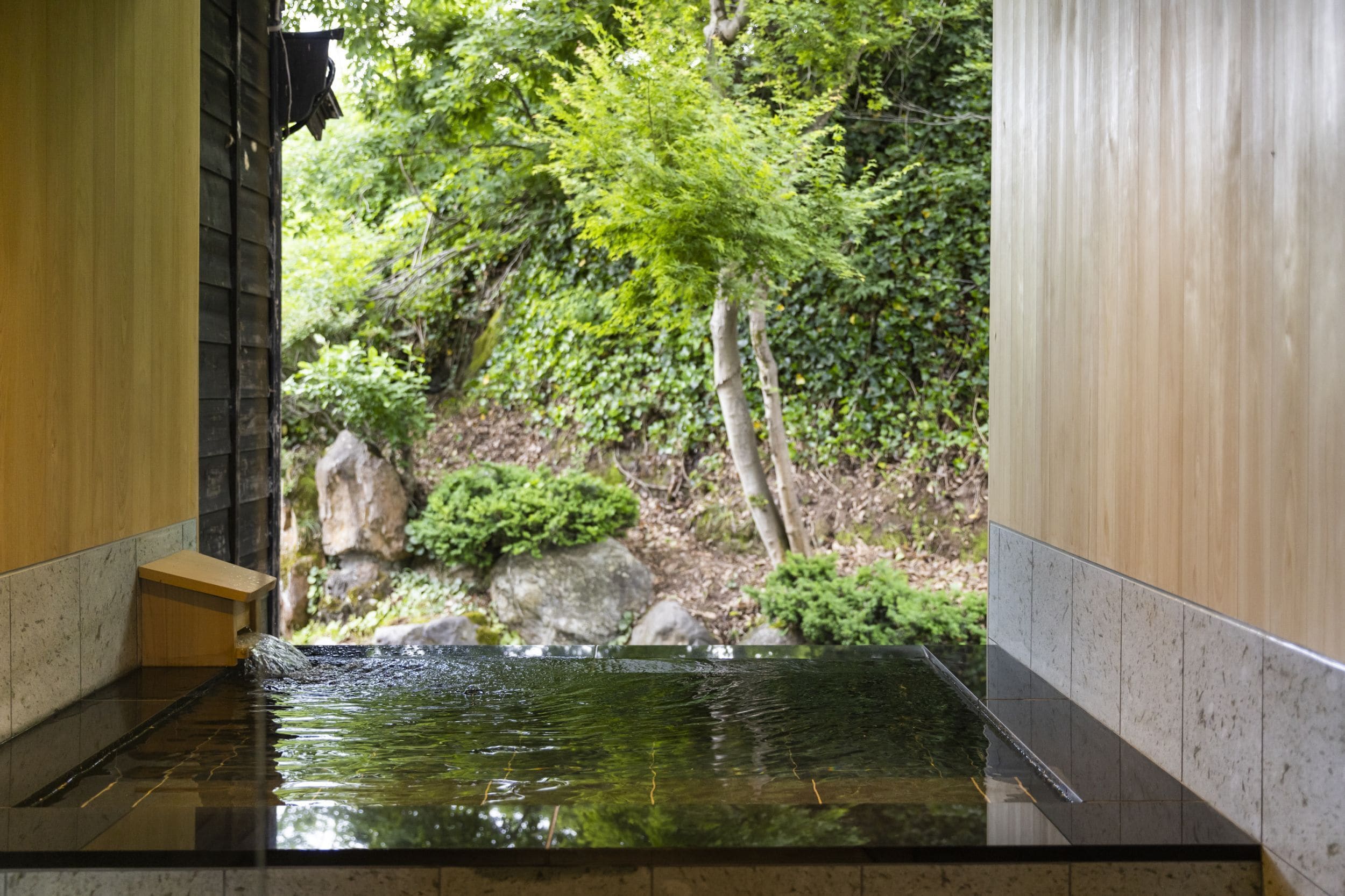 A tranquil indoor water feature with a view of a lush garden.