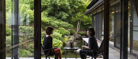 Two people seated at a table with a view of a garden and a pond.