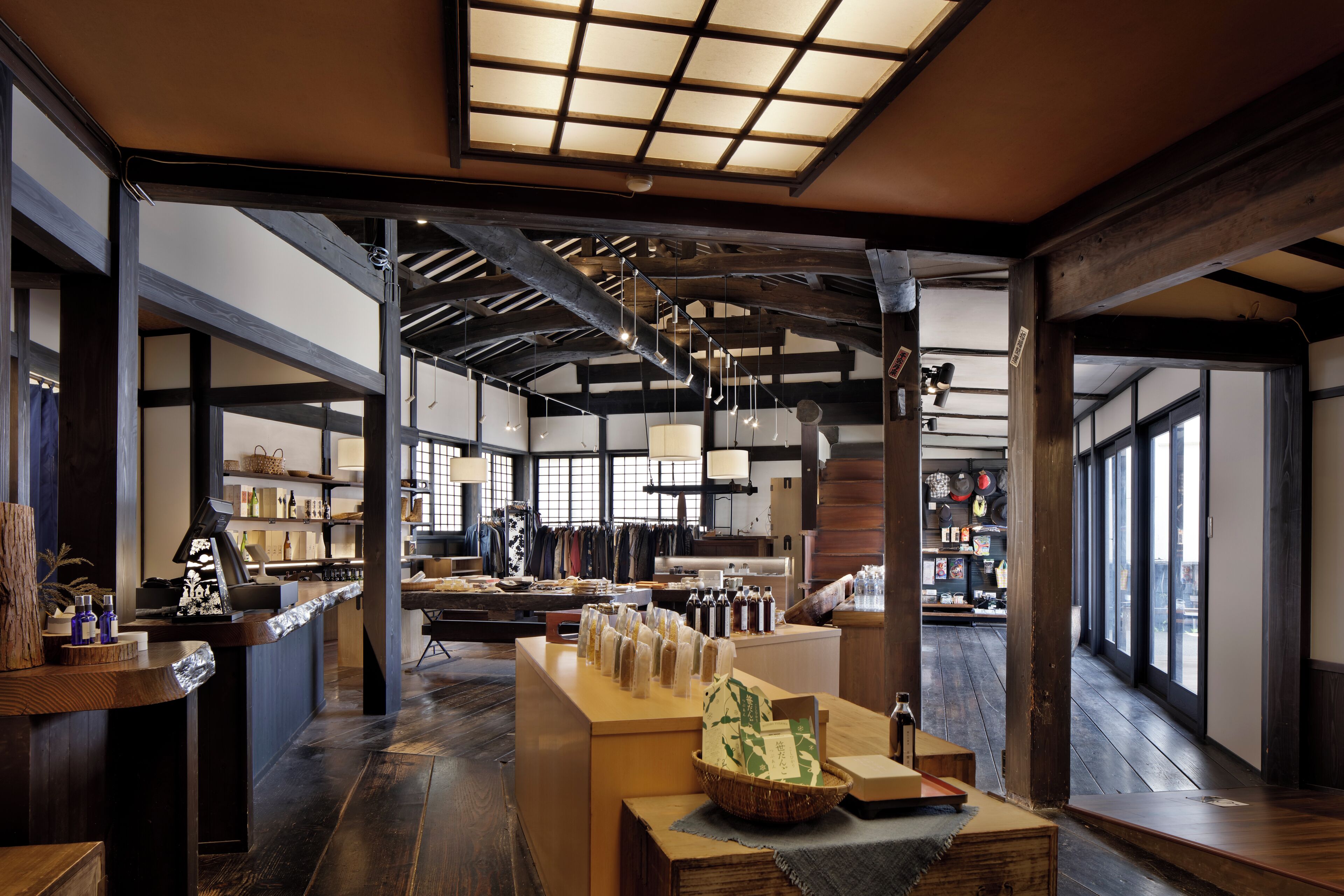 A spacious interior with wooden beams, a reception desk, and a view through large windows.