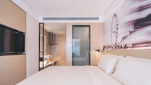 Habitació d'hotel moderna amb un llit gran, una televisió, un bany amb mirall i una obra d'art penjada a la paret amb una noria.