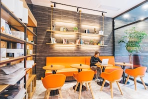 Ein modernes Interieur mit einer Holzregal, orangefarbenen Sitzgelegenheiten und einem Laptop auf einem Tisch.