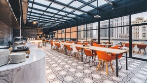 Un restaurant modern amb un sostre alt i grans finestres que ofereixen vistes a la ciutat.
