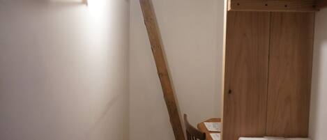 A narrow room with wooden beams on the ceiling, a wooden chair, and a small table with a folded white cloth.