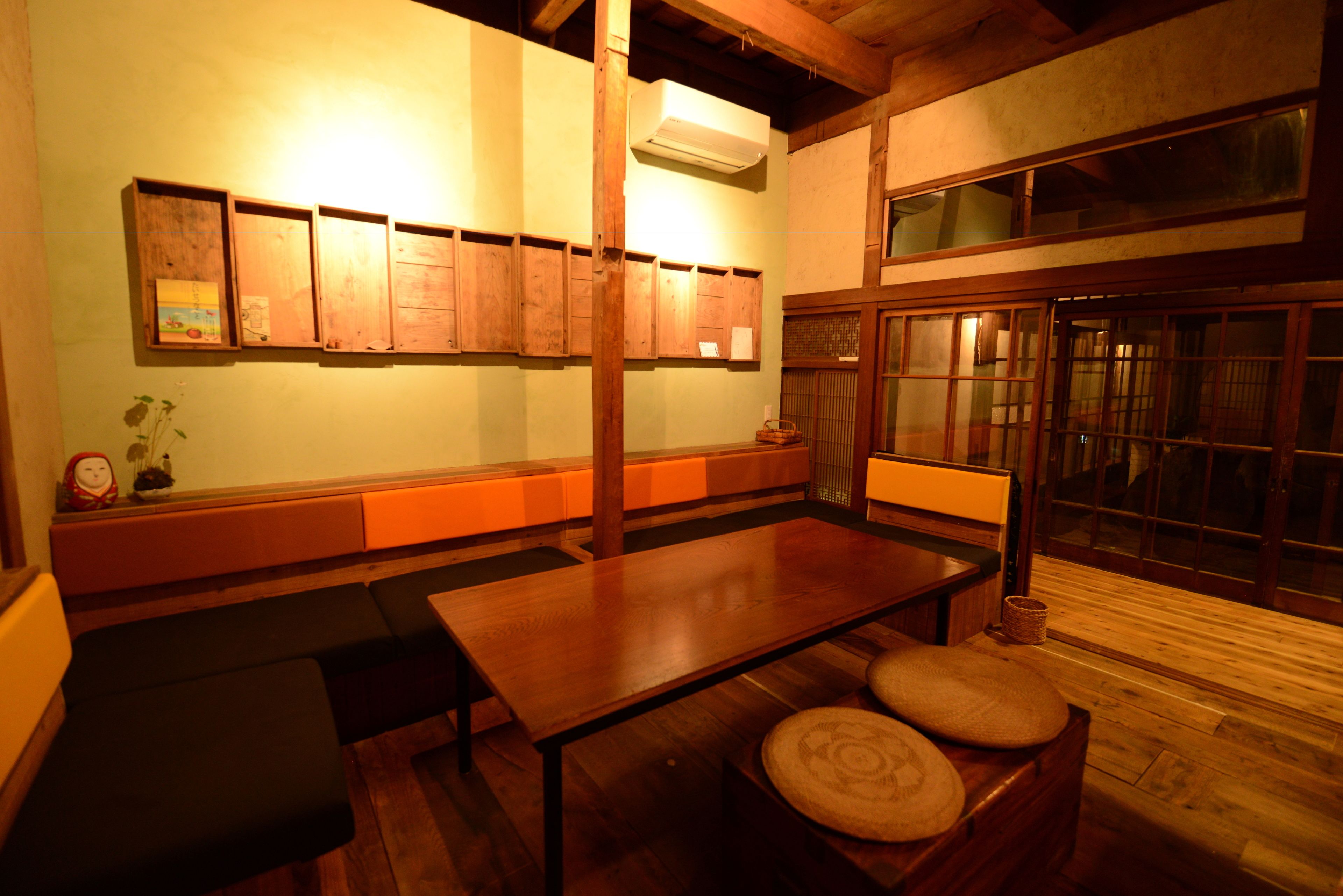 A traditional Japanese room with tatami flooring, a low table, cushions, and sliding doors.