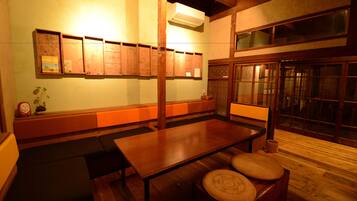 A traditional Japanese room with tatami flooring, a low table, cushions, and sliding doors.