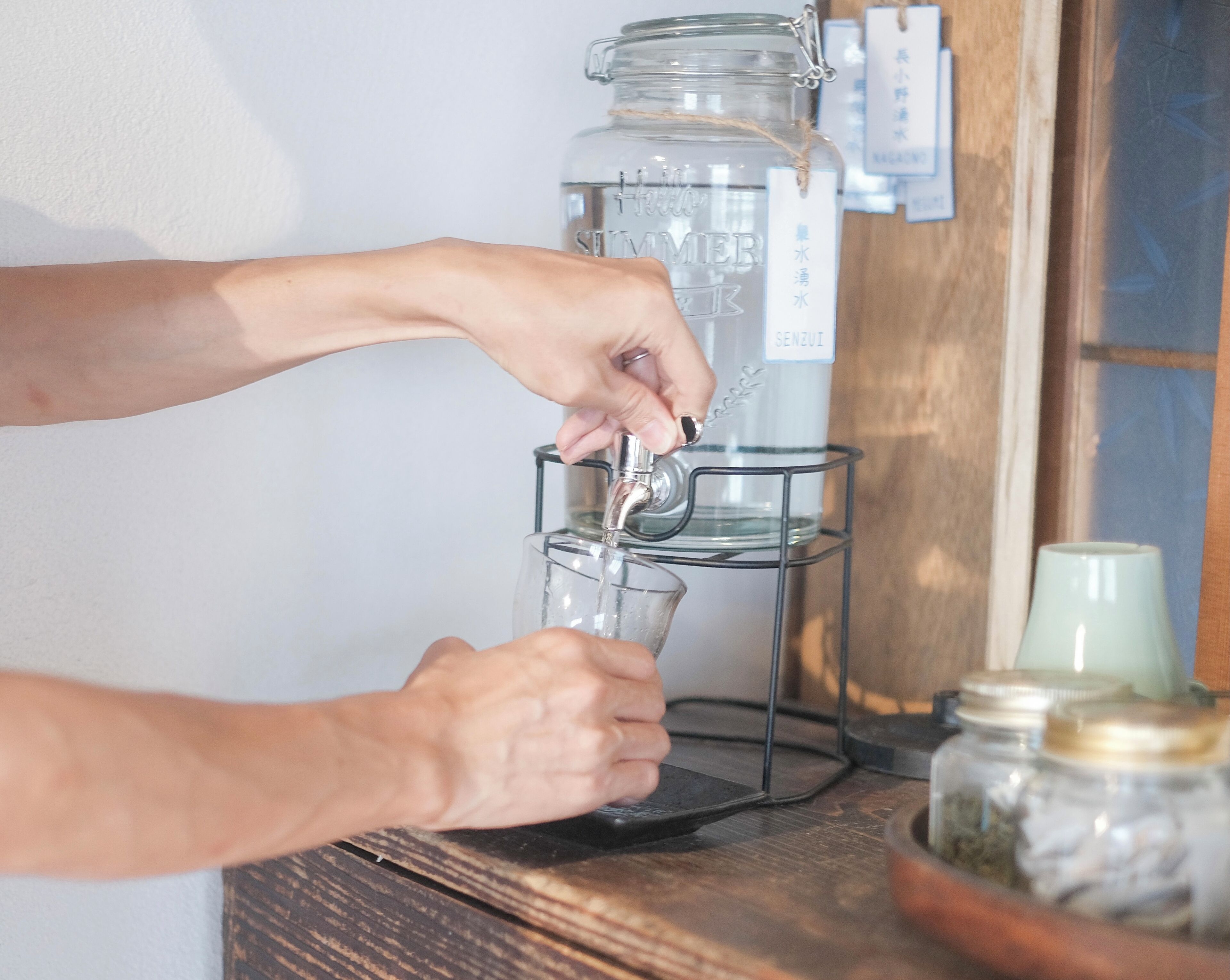 A person filling a glass with water from a dispenser.