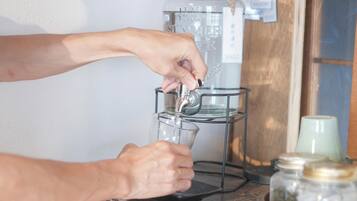 A person filling a glass with water from a dispenser.