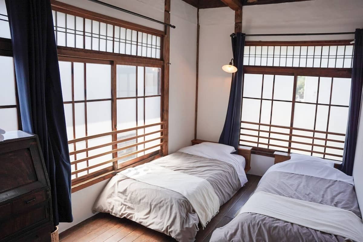 Een traditionele Japanse kamer met tatami vloeren, een laag houten bed met futon en shoji schermen.