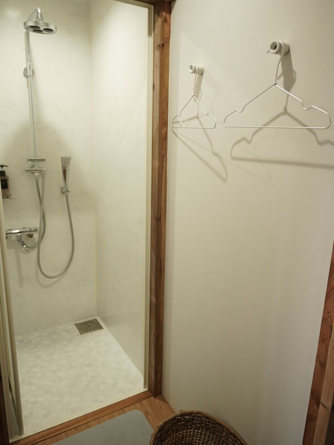 A shower area with a wooden frame, a hanging showerhead, and a shower control panel.