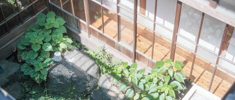 Un jardin japonais traditionnel, avec des allées pavées de pierres, des plantes vertes et des éléments en bois.