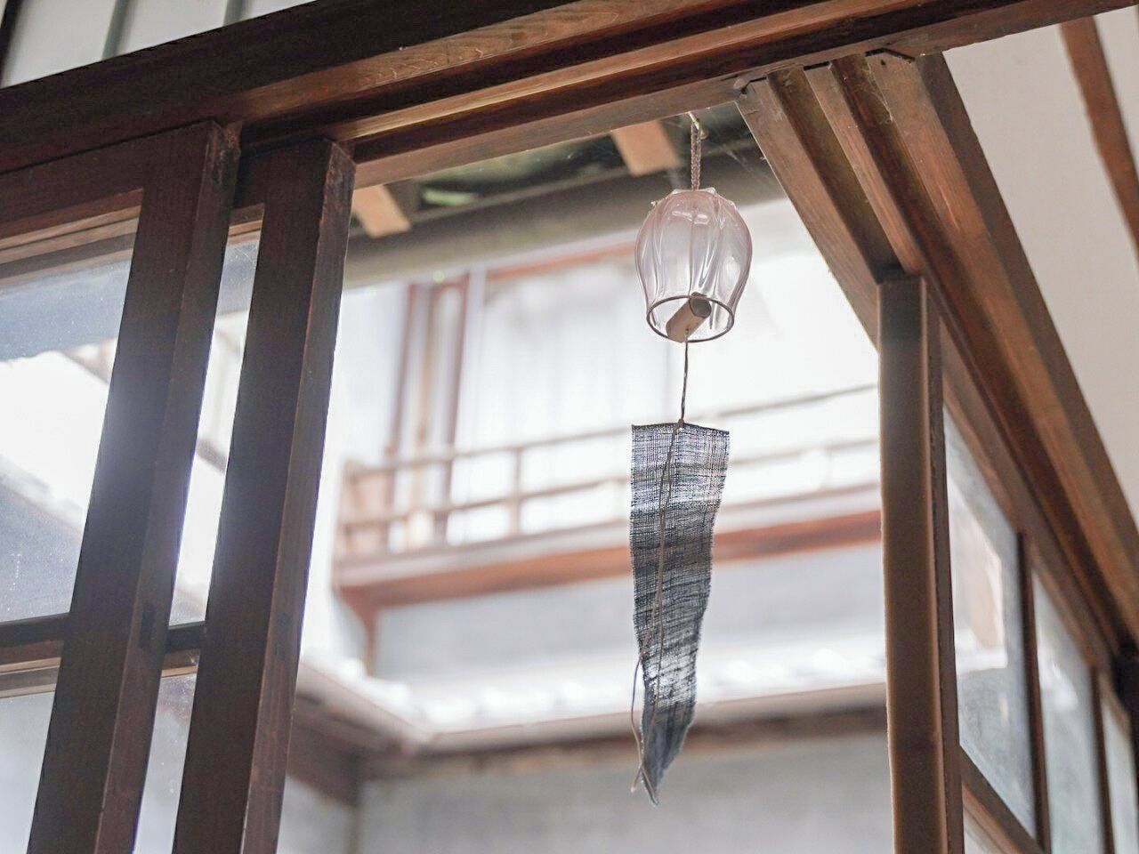 A hanging light fixture in a room with wooden beams and a window.
