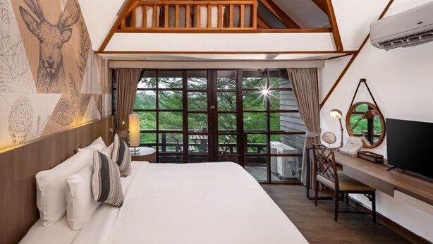 Quarto com cama grande, escrivaninha e varanda com vista.