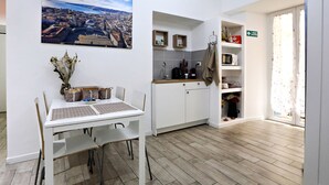 A modern kitchen with white cabinets, a dining table with chairs, a coffee machine, and a view of a cityscape. - Relais Villa Borghese (Rome)