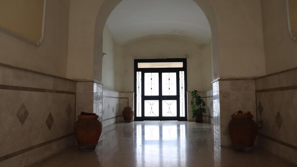 A hallway with a high ceiling, tiled walls, and a large arched doorway leading to a bright room. There are two large vases on the floor. - Relais Villa Borghese (Rome)