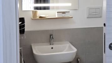 A bathroom with a white sink, a mirror, a towel, and a toilet.