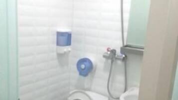 A small, compact bathroom with a toilet, a sink, and a shower.