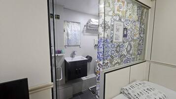 A small, compact room with a bed, a sink, and a mirror.