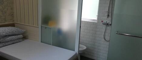 Ein kleines, kompaktes Zimmer mit einem Einzelbett, einer Duschgelegenheit und einem WC.