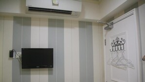 Un baño con pared a rayas, un televisor montado y una puerta decorada con un colgador de metal.