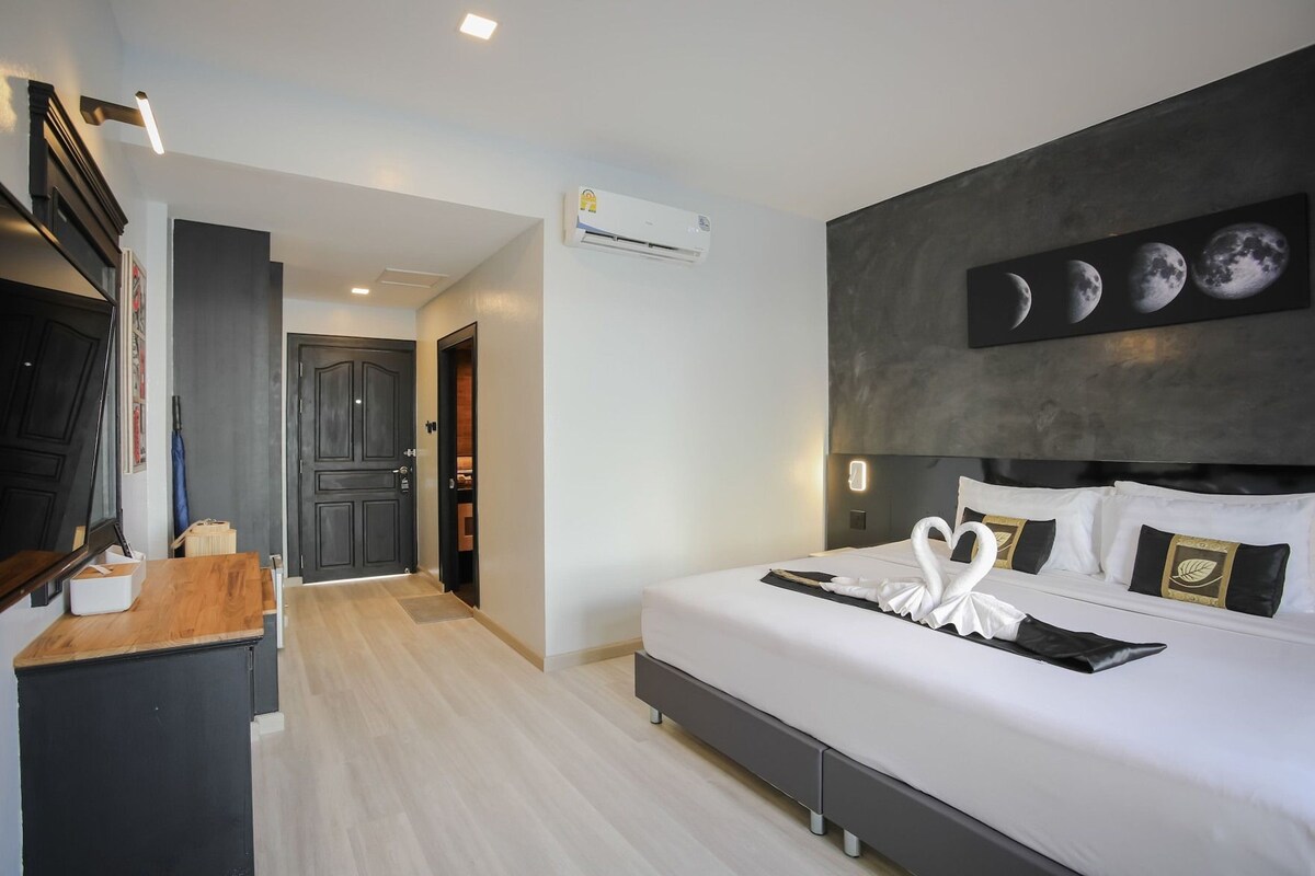 Habitación de hotel con cama, escritorio, espejo y aire acondicionado de pared.