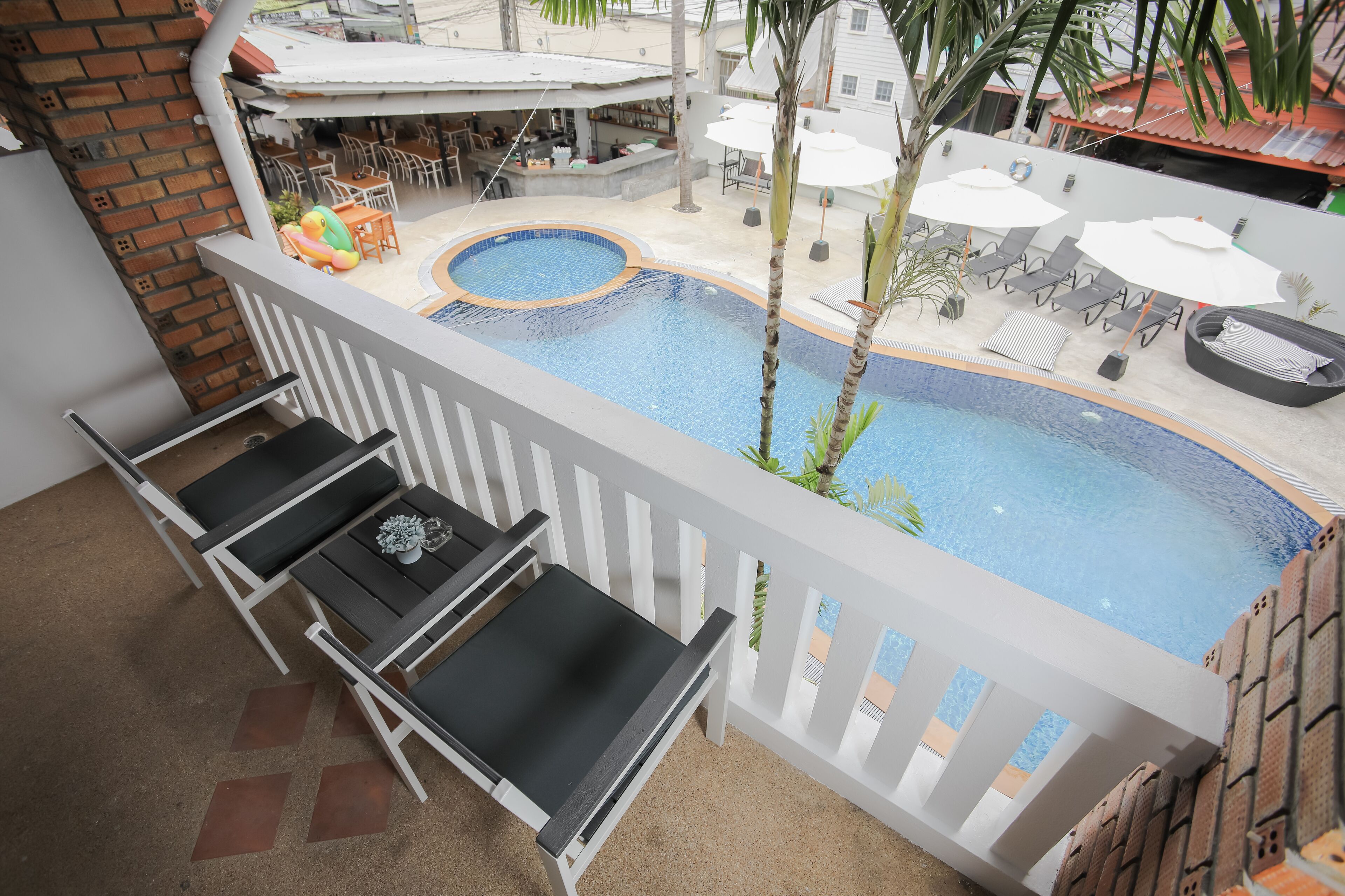 A pool area with lounge chairs, a small pool, and a bar area with outdoor seating.