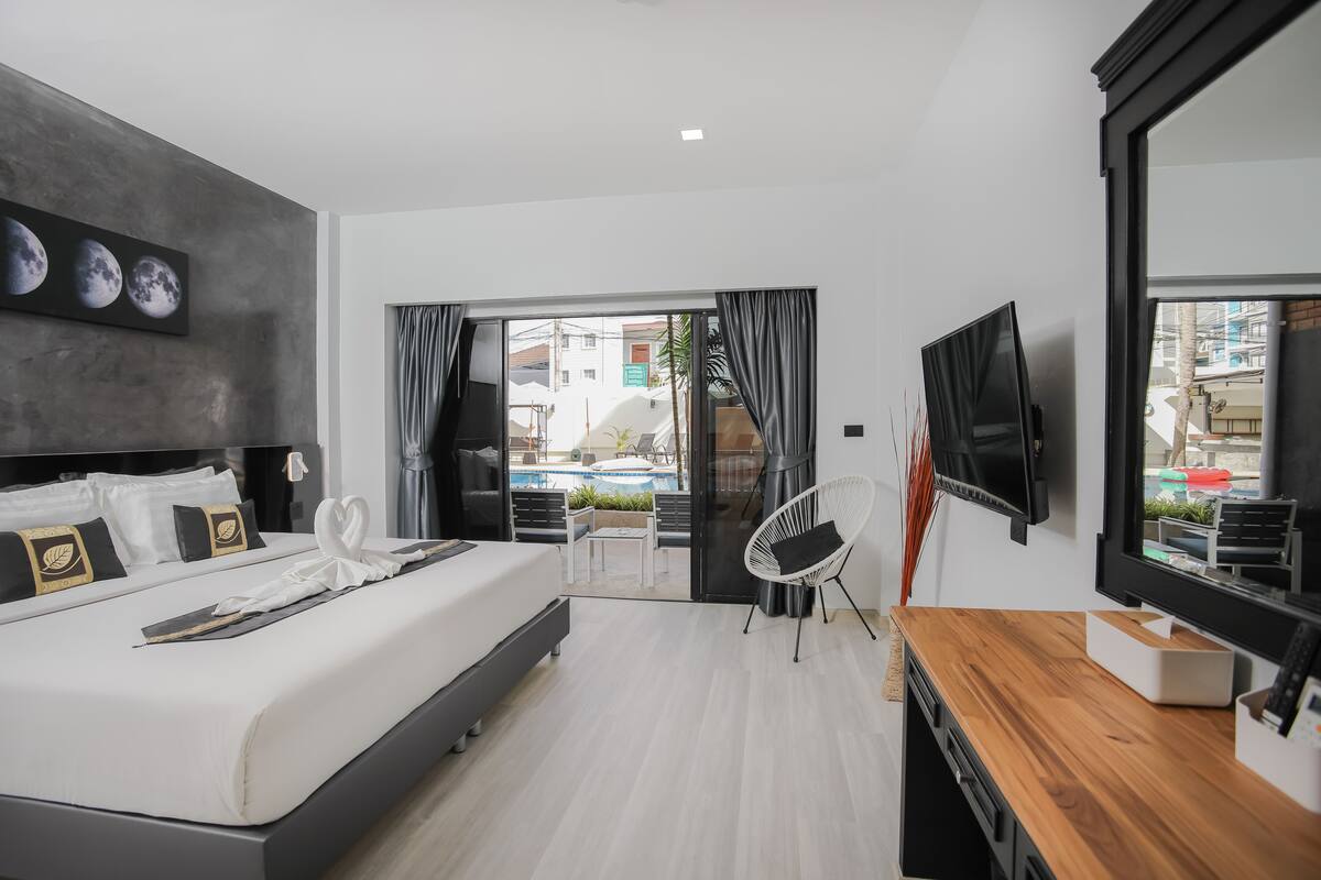 Habitación de hotel moderna con cama, escritorio de madera, televisión y vista al área exterior.