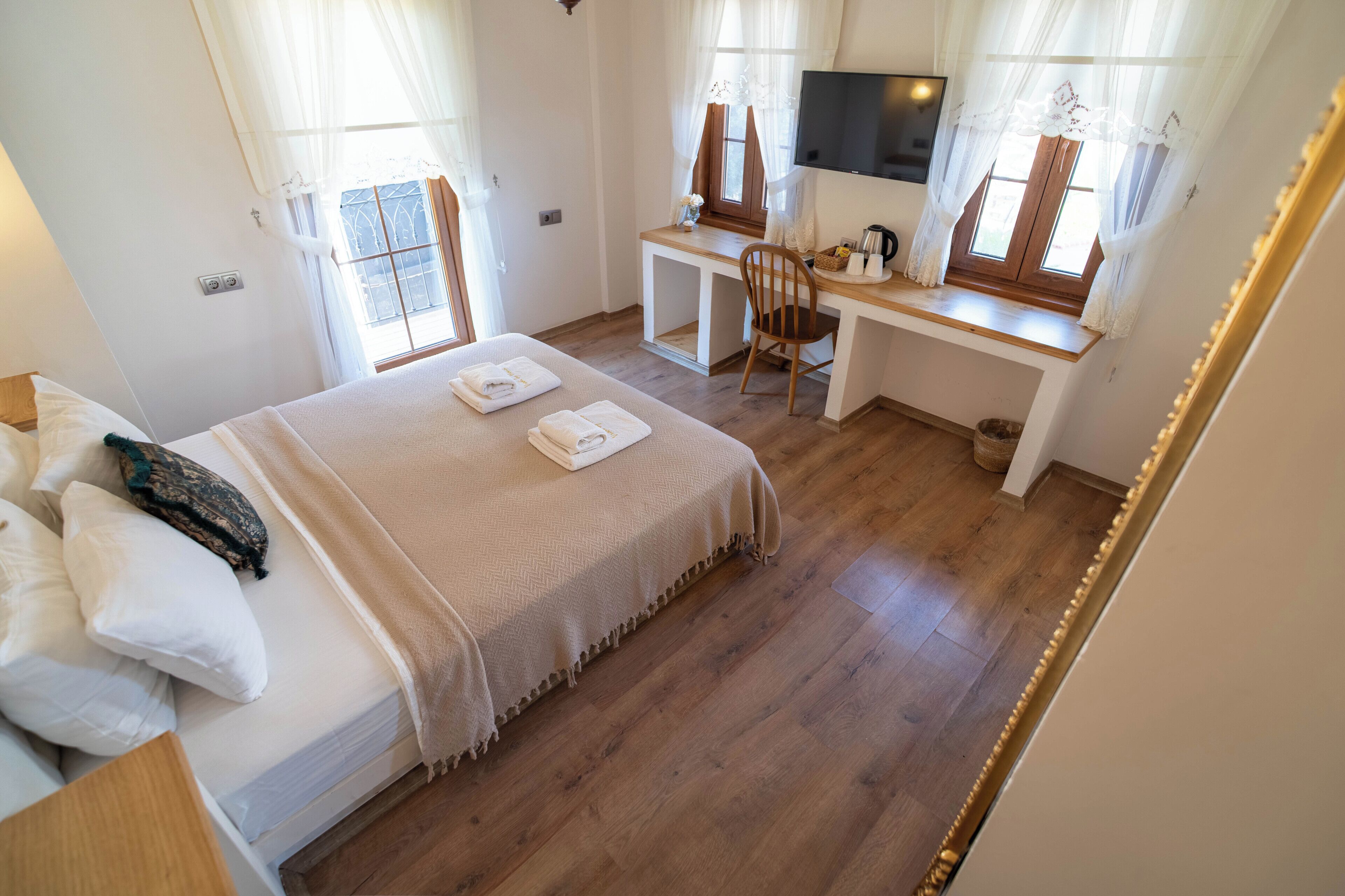 A hotel room with a bed, a desk, a chair, a TV, and a window.